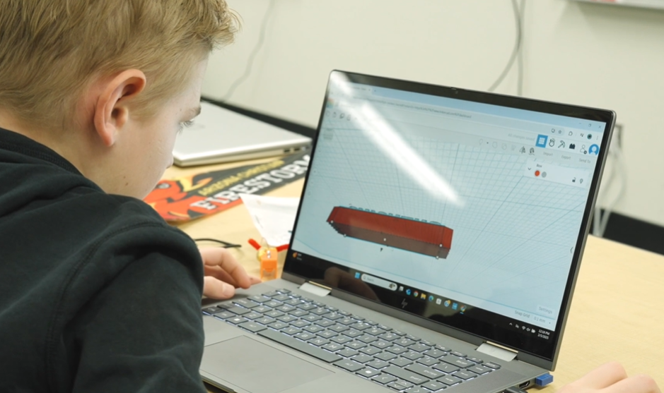 A high school student works on an assignment on his laptop